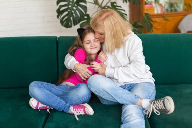 Mutlu torun ve büyükanne kanepeye oturmuş komik pozlar veriyorlar. Büyükannem evde torunuyla eğleniyor. Yaşlılar, aile ve nesil kavramı..