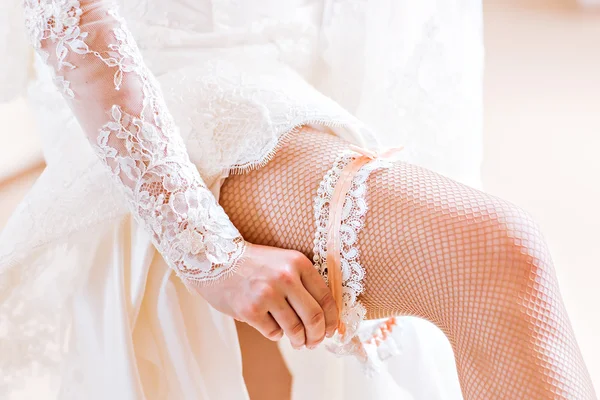 bride dresses garter on the leg.