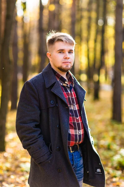 Hombre usando un abrigo en el parque de otoño — Foto de Stock