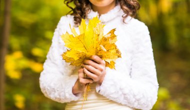 bir akçaağaç sonbahar yaprakları tutan kadın