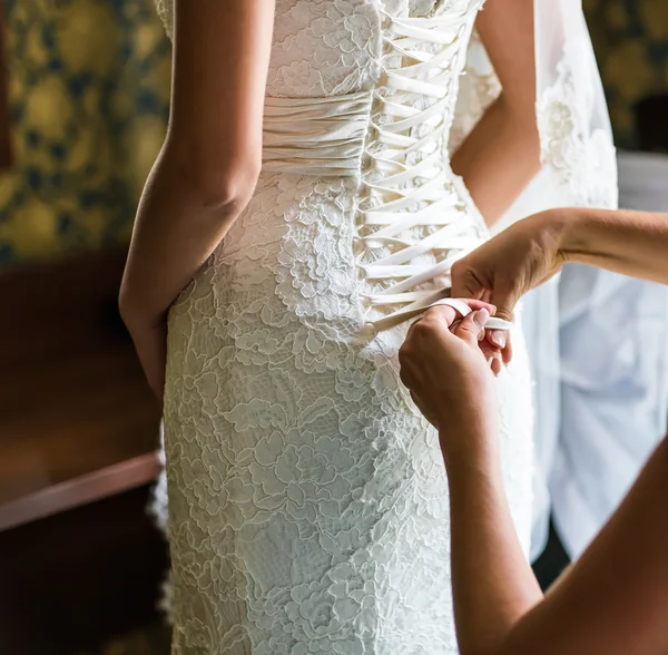 Bridesmaid is helping the bride to dress — Stock Photo, Image