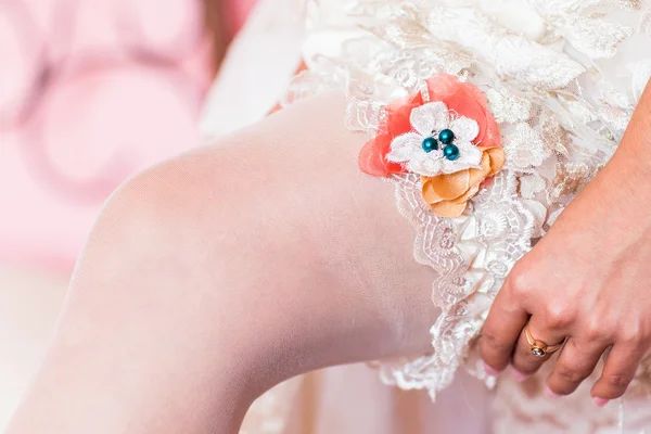 Bride dresses garter on the leg. — Stock Photo, Image