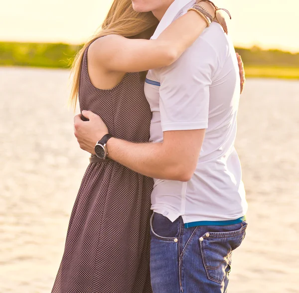 Счастливая пара обнимается, стоя на берегу реки — стоковое фото