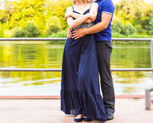 Pareja feliz abrazándose mientras está de pie en la orilla de un río — Foto de Stock