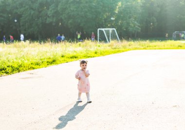  Küçük kız parkta yürüyor.