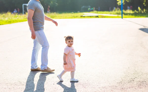 Bébé fille marche dans un parc d'été avec son père — Photo