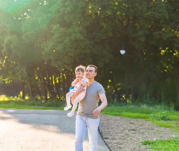 Baby girl walking in a summer park with her father — Stock Photo, Image