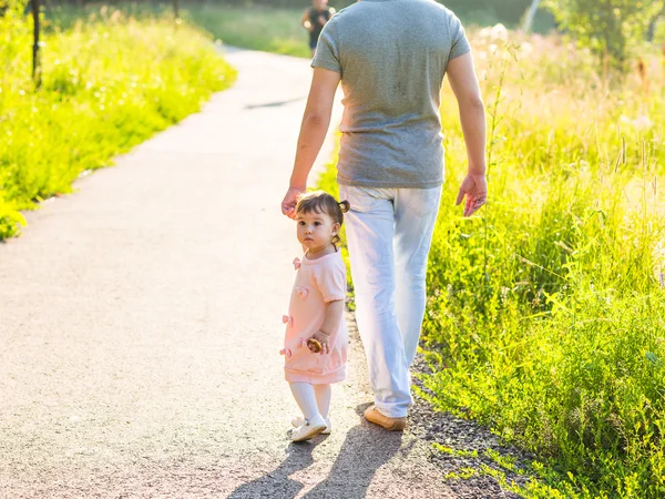 Bambina che cammina in un parco estivo con suo padre — Foto Stock