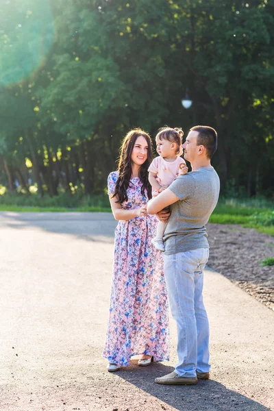 Glückliche junge Familie spaziert durch den Park. — Stockfoto