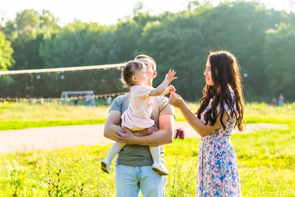 Glad ung familj promenader i parken. — Stockfoto