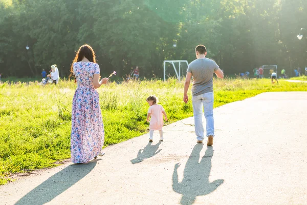 Glad ung familj promenader i parken. — Stockfoto