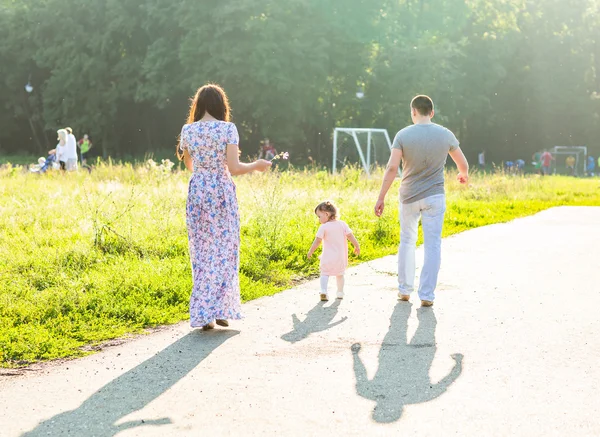 Glad ung familj promenader i parken. — Stockfoto