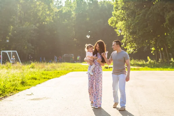 Glückliche junge Familie spaziert durch den Park. — Stockfoto