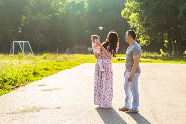 Glückliche junge Familie spaziert durch den Park. — Stockfoto