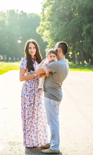 Jovem família feliz andando no parque. — Fotografia de Stock