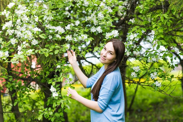 Ritratto di ragazza bruna primaverile in piedi all'aperto tra gli alberi in fiore . — Foto Stock