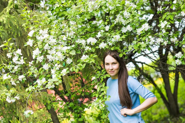Portret van voorjaar brunette meisje permanent buiten in de bloeiende bomen. — Stockfoto
