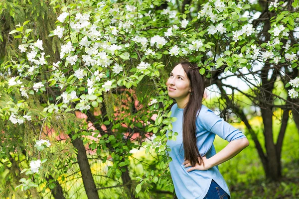 Ritratto di ragazza bruna primaverile in piedi all'aperto tra gli alberi in fiore . — Foto Stock