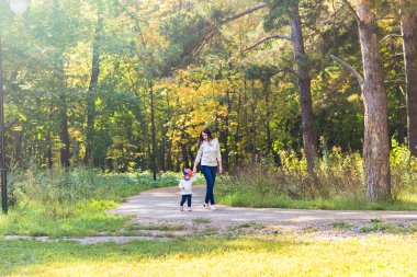 mutlu aile anne çocuk ile çalışan ve sonbahar park üzerinde oynarken küçük kızı