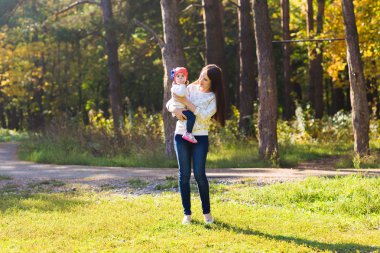 mutlu aile anne çocuk ile çalışan ve sonbahar park üzerinde oynarken küçük kızı