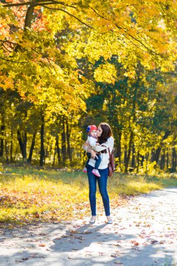 mutlu aile anne çocuk ile çalışan ve sonbahar park üzerinde oynarken küçük kızı