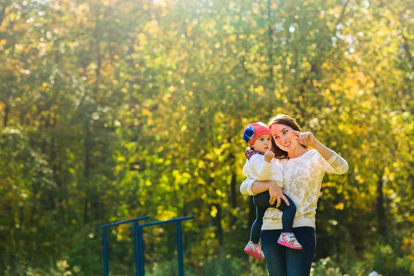 Glad familj mor med barn lilla dotter springa och spela på hösten park — Stockfoto