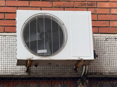 Tuğla bir duvarda açık hava klima ünitesi. Kentsel altyapı, havalandırma sistemi ve enerji teknolojisi iklim kontrolü ve endüstriyel tasarımı temsil etmektedir.