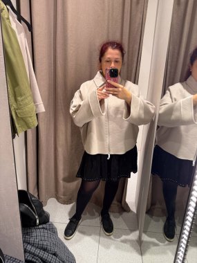 Deneme odasında krem rengi ceket deniyorum. Kişisel tarzın keşfi, vücut güveni ve modanın kendini ifade etme şekli gelişigüzel minimalizm ve nötr tonlar ile