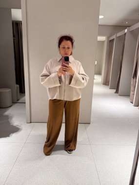 Açık renk ceketli ve kahverengi pantolonlu bir kadın. Uyum, doku ve denge üzerine modern yansıma bilinçli çağdaş yaşam tarzı ve moda estetiği