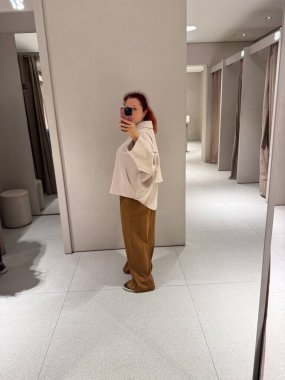 Koyu renk pantolonlu, bej ceketli yan profil. Kibar hareketin, orantı dengesinin ve sonbahar modasında duygusal yumuşaklığın temsili