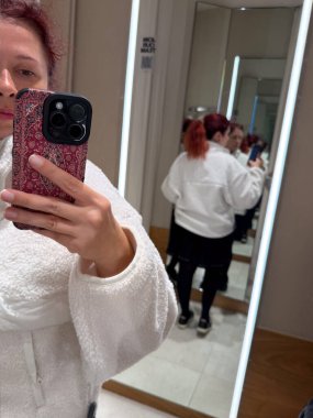 Örtü ceketi ayarlayan kadının ayna yansıması. Kişisel gözlem, kimlik ve duygusal farkındalık için görsel metafor modern asgari estetik yoluyla