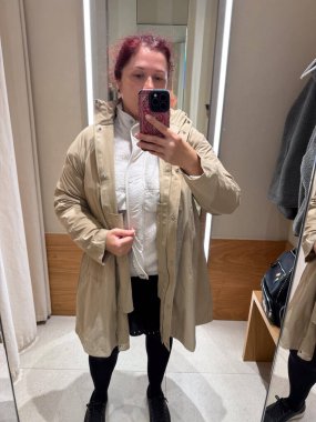 Aynada kapüşonlu bej bir yağmurluk deniyordum. Modern minimalizm ve yumuşak pratik tasarım ile ifade edilen koruma, adaptasyon ve bireysellik kavramı