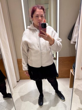 Deneme odasında montunu ayarlayan kadının yakın çekimi. Moda ve minimalist zarafetin dokunsal algısı ile dokunun keşfi, öz farkındalık ve kimlik