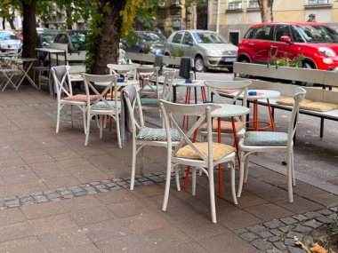 Şehir caddesinde renkli sandalyeleri ve boş masaları olan bir açık kafe terası. Kentsel yaşam tarzı, rahatlık ve günlük basitlik rahat bir sosyal çevrede