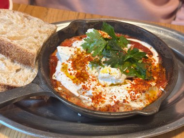 Shakshuka ve demir tavada servis edilen ekmek. Akdeniz aroması, tazelik ve kafe kahvaltı yemeğinde ev yapımı konfor..