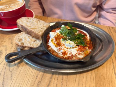 Shakshuka ve demir tavada servis edilen ekmek. Akdeniz aroması, tazelik ve kafe kahvaltı yemeğinde ev yapımı konfor..