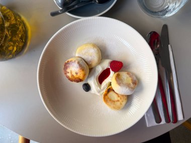Kremalı ve böğürtlenli peynirli kekler masanın üstünde. Tatlı tatlı, rahat kahvaltı ve kafede rahatlama anı..