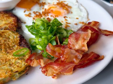 Kızarmış yumurtalı ve yeşil soğanlı kızarmış domuz pastırması. Lezzetli kahvaltı ayrıntıları, tazelik ve leziz doku.