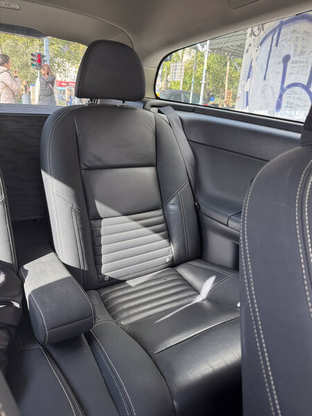 Black leather car seat in sunlight inside parked vehicle. Comfort, transportation lifestyle and modern design in everyday automotive interior