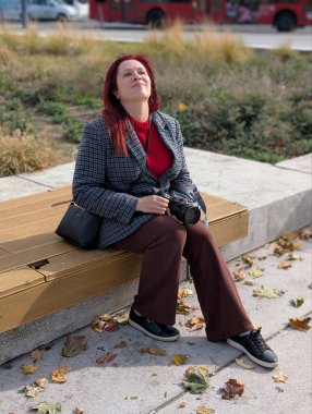 Güneşli bir günde bankta oturan bir kadın. Rahatlama, yaratıcılık ve ilham günlük açık hava yaşam tarzı ve fotoğrafçılık tutkusundan gelir.