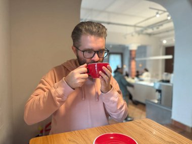 Kafe masasında kahve içen bir adam. Günlük rutin rutinlerde sıcaklık, yansıma ve basit bir zevk anı