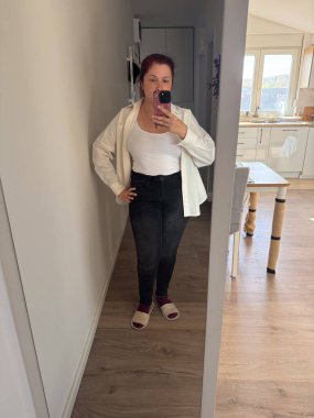 Aynanın karşısına geçmiş sıradan bir ev elbisesi giymiş, sabah ışıklarıyla bekleyen bir kadın. Günlük basitlik, özgüven ve sakin bir ev hayatının özgünlüğü.