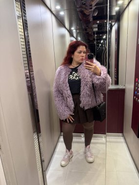 Asansörde eflatun kürk manto giyen bir kadın. Kendine güven, tarz ve bireysellik şakacı şehir modasıyla ifade edilir.