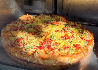 Fırın vitrininde peynirli ve biberli taze pişmiş pizza. Rahatlatıcı yemek, İtalyan mutfağı ve ev yapımı lezzet.