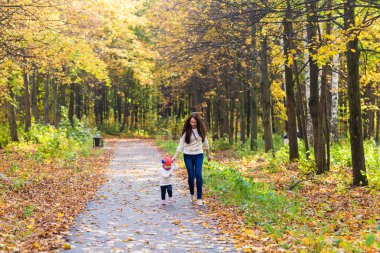 Genç anne ile bebeği bir sonbahar Park yürüme