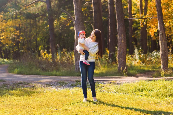 秋の公園で彼女の赤ちゃんを連れて歩いて若い母親 — ストック写真