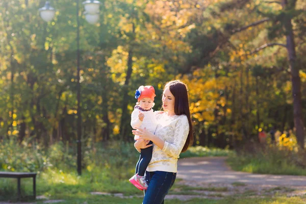 Młoda matka chodzenie z jej dziecko w parku jesień — Zdjęcie stockowe