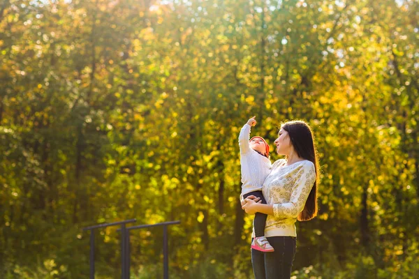 Jovem mãe caminhando com seu bebê em um parque de outono — Fotografia de Stock