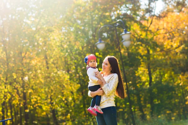 Ung mamma med sitt barn i en park på hösten — Stockfoto