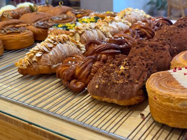 Pastane vitrininde çeşitli kruvasanlar ve çikolatalı pastalar. Zanaatkârlık ve sabah keyfi..